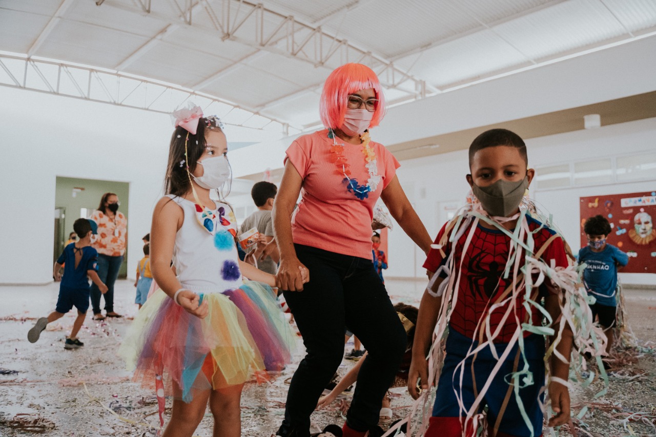 Crianças brincam com serpentina durante bailinho carnavalesco na Creche-Escola Sementinha