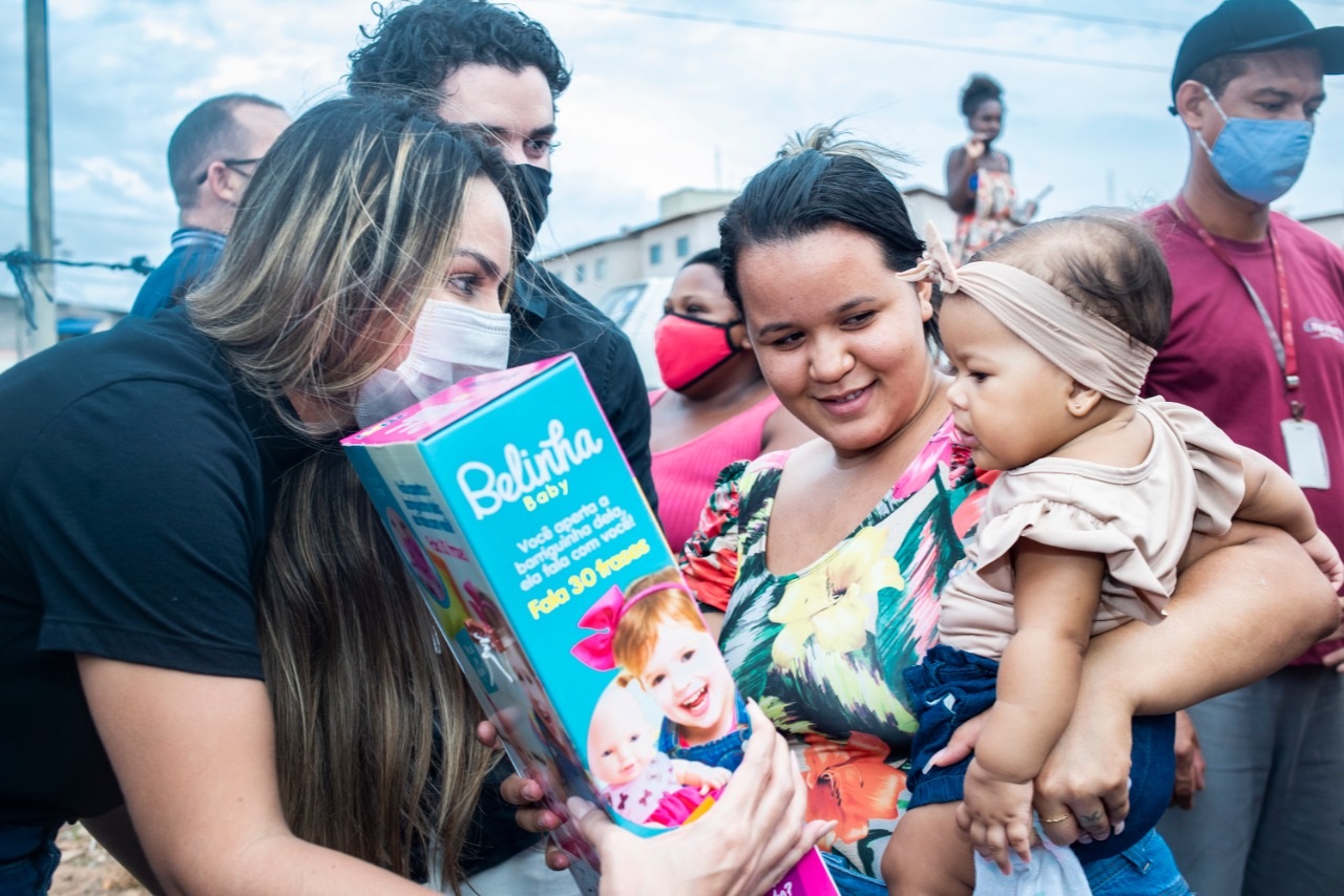 A presidente do Gedema entrega brinquedo à pequena moradora da Ilhinha