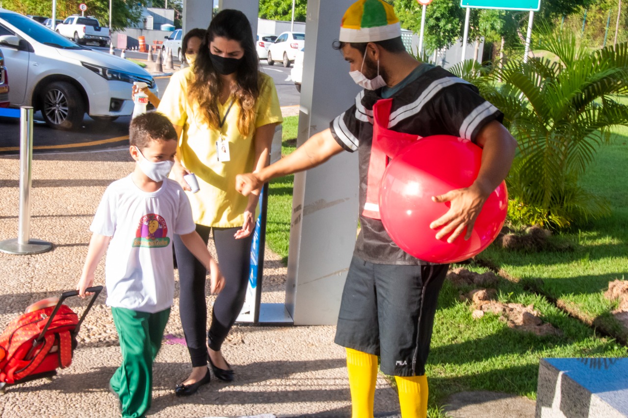 Criança sendo recepcionada por professor caracterizado como personagem de TV na Creche-Escola Sementinha