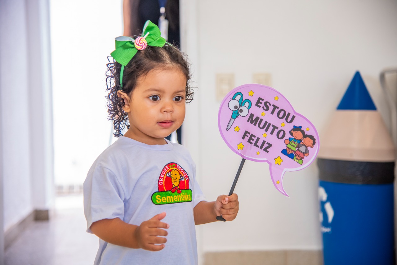 Aluna com placa de boas-vindas preparada pela equipe da Sementinha