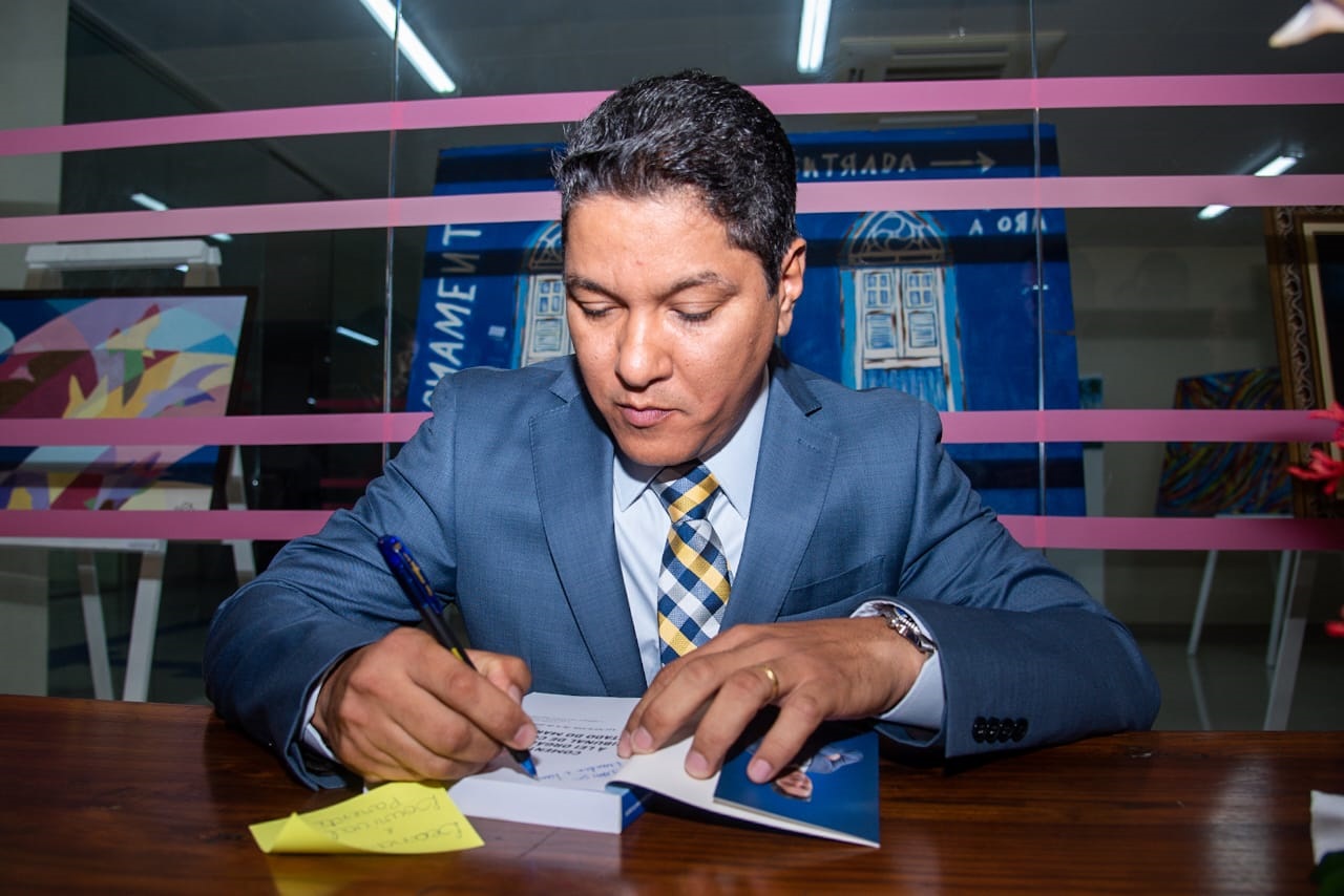 O autor da obra, Flávio Olímpio, autografa livro durante a cerimônia de lançamento da publicação 