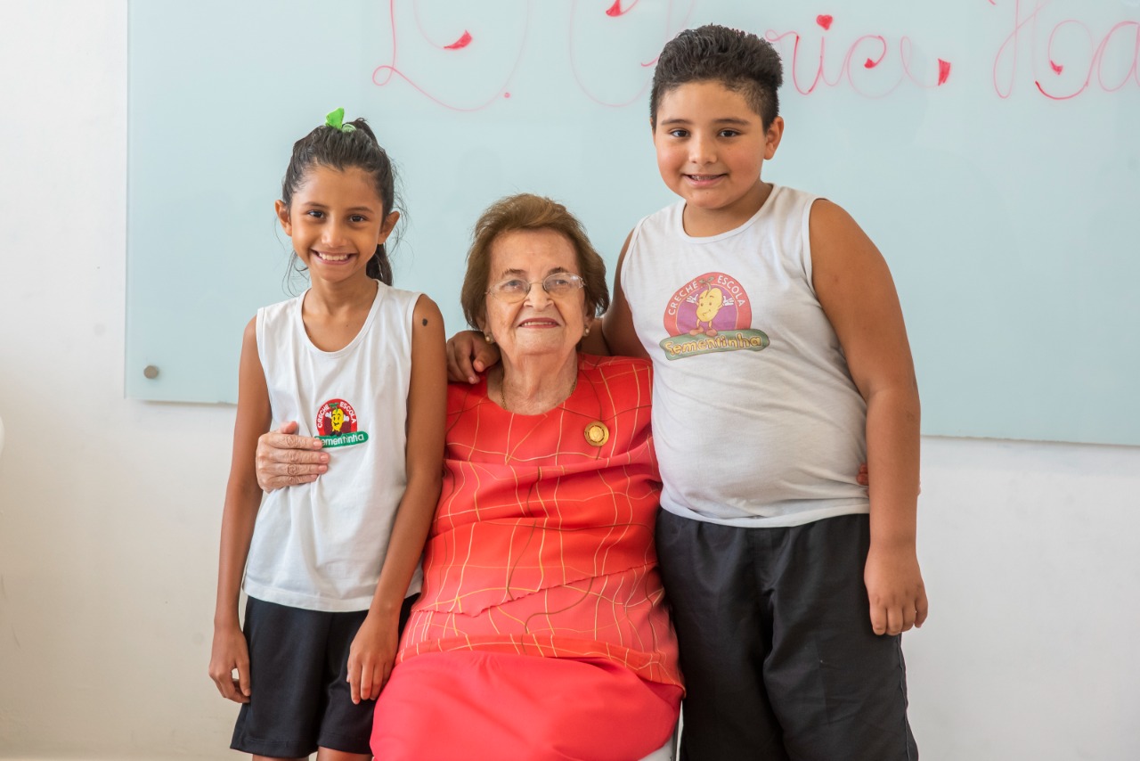 A fundadora da Creche-Escola Sementinha recebendo o carinho de alunos da instituição 